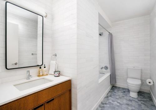 La salle de bains est pourvue d'un lavabo, de toilettes et d'un miroir. dans l'établissement Modern Studio Apartment At East Side, à New York