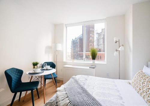 - une chambre blanche avec un lit, une table et des chaises dans l'établissement Modern Studio Apartment At East Side, à New York