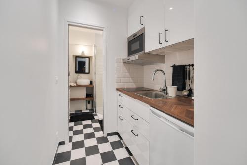 a kitchen with white cabinets and a checkered floor at Studio "Café Papillon"-Paris 15 in Paris
