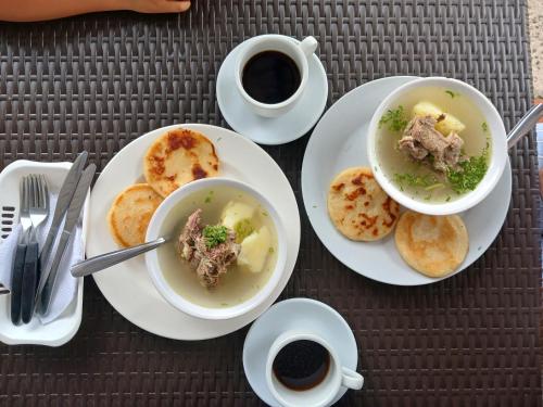 una mesa con dos platos de sopa y dos tazas de café en Hotel campestre la Maria, en Villavicencio