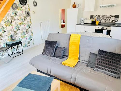 - un salon avec un canapé gris et des oreillers jaunes dans l'établissement La Maisonnette Un Séjour à Part, à Longeville-lès-Metz