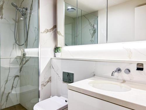 a white bathroom with a sink and a shower at Close To Mel Uni 2br 2ba Parking Balconywifigy in Melbourne