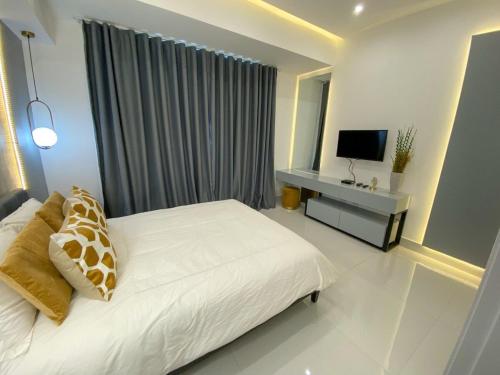 a white bedroom with a bed and a television at Moderno y acogedor apartamento en Santo Domingo. in Santo Domingo