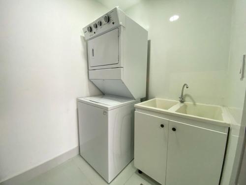 eine weiße Küche mit einer Spüle und einem Kühlschrank in der Unterkunft Moderno y acogedor apartamento en Santo Domingo. in Santo Domingo