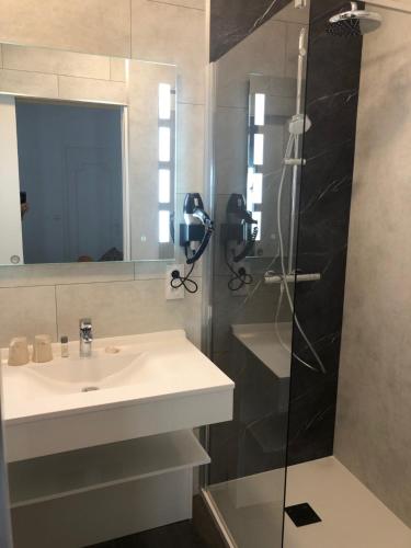 uma casa de banho com um lavatório e um chuveiro em Cit'Hotel Atlantis em Royan