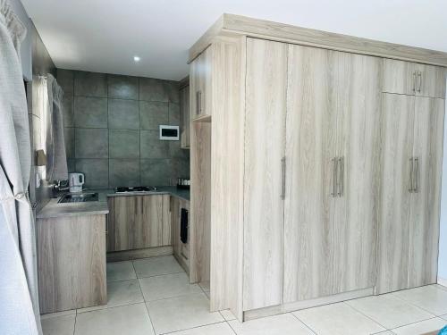 uma cozinha com armários de madeira e um lavatório em Royal Mansion Lodge em Joanesburgo
