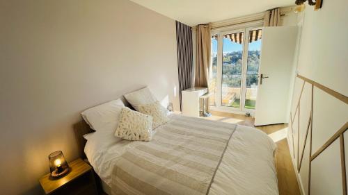 1 dormitorio con cama y ventana grande en Appartement cosy - 3 chambres - 700m centre Ecully, en Écully