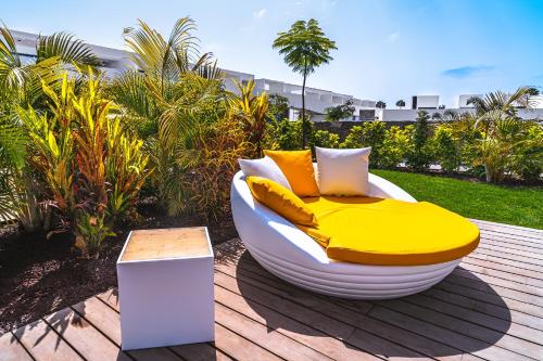 una cama amarilla y blanca sentada en una cubierta en Resort Cordial Santa Águeda & Perchel Beach Club, en La Playa de Arguineguín