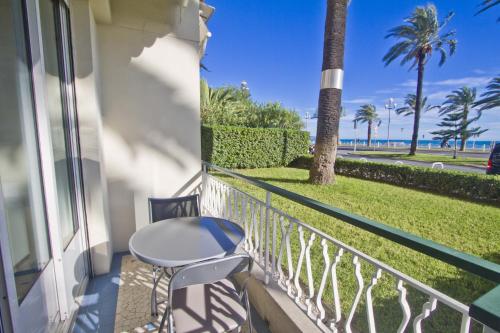 a balcony with a table and a view of the ocean at Garden Floor Condo with Promenade Sea View in Nice