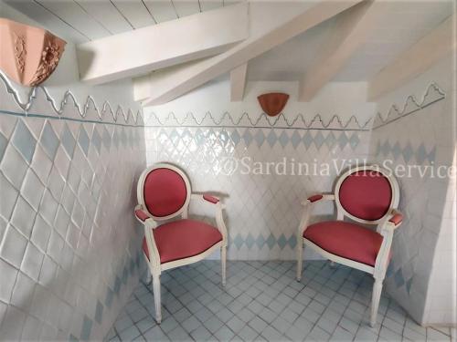 two red chairs sitting in a room with tiles at Villa Mare Blu - Porto Rotondo in Porto Rotondo