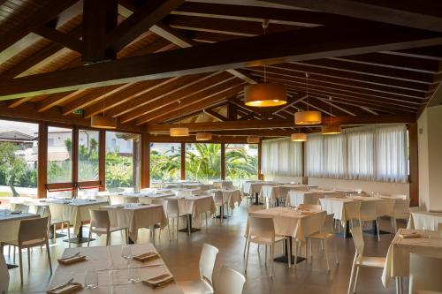 una sala da pranzo con tavoli e sedie bianchi di VOI Baia di Tindari Resort a Furnari