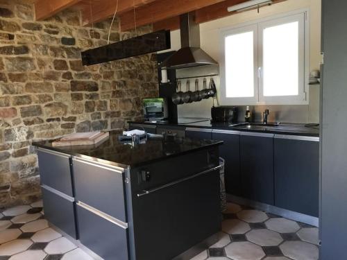 une cuisine avec des placards bleus et un mur en briques dans l'établissement Penty Kael, à Crozon