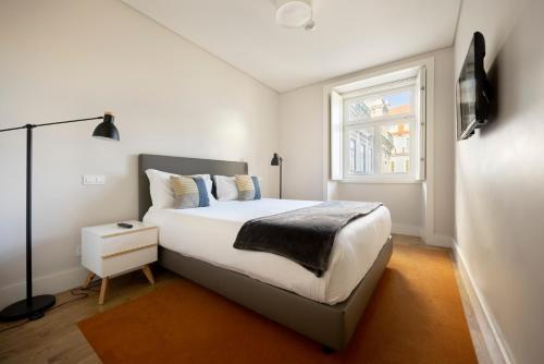 a white bedroom with a bed and a window at Chiado Square Apartments | Lisbon Best Apartments in Lisbon