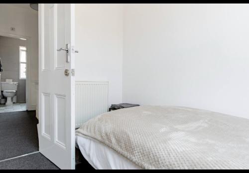 a white bedroom with a bed and a bathroom at Devondale Road, Penny Lane area in Liverpool