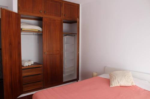 1 dormitorio con armario de madera y cama en Guesthouse Felicidade en Lagos