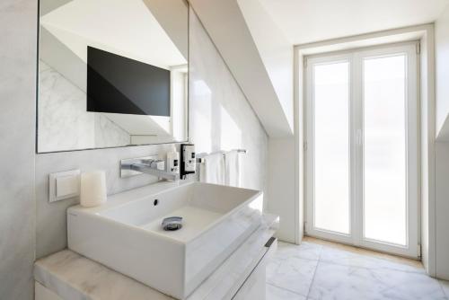 a white bathroom with a sink and a tv at Chiado Square Apartments | Lisbon Best Apartments in Lisbon