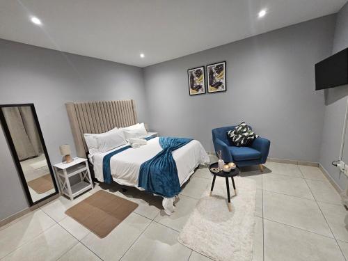 sypialnia z łóżkiem i niebieskim krzesłem w obiekcie Royal Mansion Lodge w mieście Johannesburg