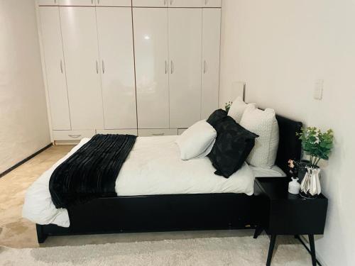 a bedroom with a black bed with white sheets and pillows at Marble Nights 2 in Johannesburg