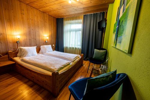 ein Schlafzimmer mit einem Bett und zwei Stühlen darin in der Unterkunft CURUNA Hotel-Garni in Scuol