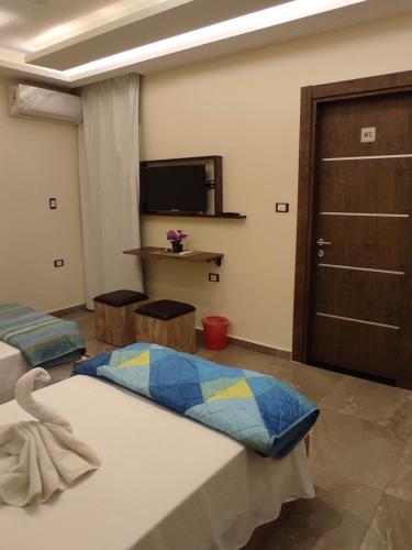 a room with two beds and a tv and a door at pyramids view suite/vista piramidi in Cairo