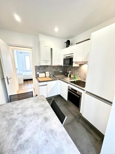 une cuisine avec des armoires blanches et un comptoir dans l'établissement Elegant Paris Pantin apartment - line 7, à Pantin