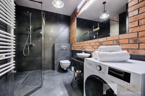 een badkamer met een douche, een toilet en een wastafel bij Fuzja V by LookAp in Łódź