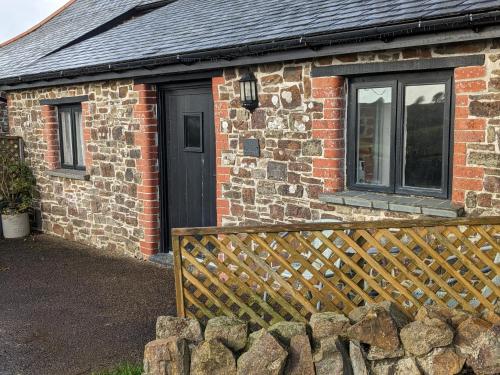 a brick house with a wooden fence in front of it at Elegant and secluded 1-Bed Cottage near Bideford in Bideford