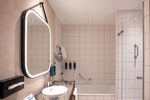 a bathroom with a shower and a sink and a tub at Hilton Cologne in Cologne