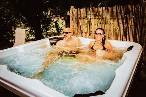 un hombre y una mujer sentados en una bañera en Cabaña espectacular, con vista al río y hot tub privado, en Linares