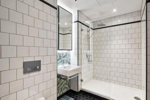 a white tiled bathroom with a sink and a shower at Livestay-Studio Apartment in Modern Development in London