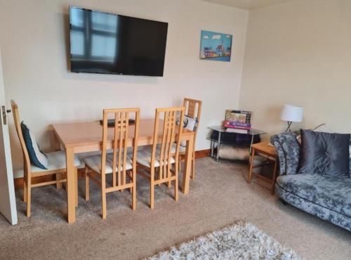 a living room with a table and chairs and a tv at Ness City Apartment in South Kessock