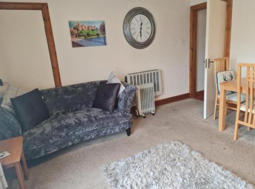a living room with a couch and a clock on the wall at Ness City Apartment in South Kessock