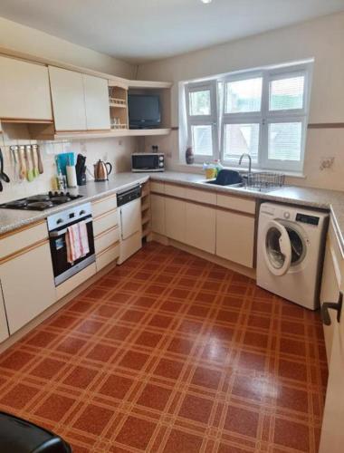 a kitchen with white cabinets and a washer and dryer at Ness City Apartment in Inverness
