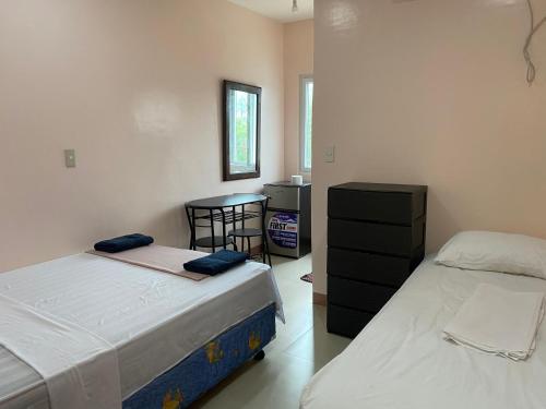 ein Schlafzimmer mit 2 Betten und einem Tisch darin in der Unterkunft Kellocks' Seaview Apartelle in Dalaguete