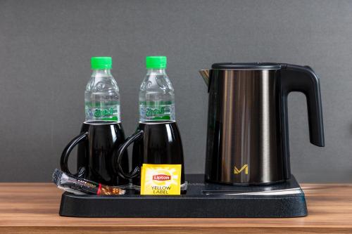 a coffee pot and two bottles of water on a tray at Ewan Dar Alhejra Hotel in Al Madinah