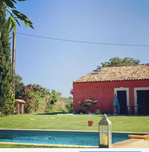 un bâtiment rouge et une piscine devant une maison dans l'établissement Villa avec Pool House au cœur des vignes - Lubéron, à La Tour-dʼAigues