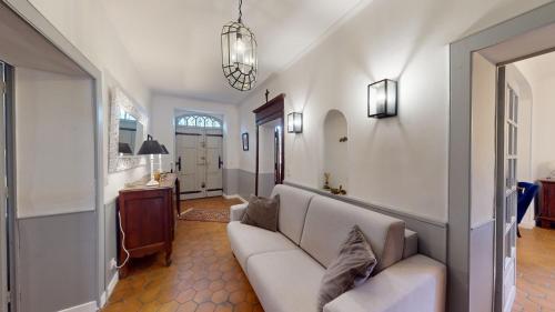 a living room with a white couch and a kitchen at Les Terrisses - Chambres d'hôtes avec piscine in Saint-Félix-Lauragais