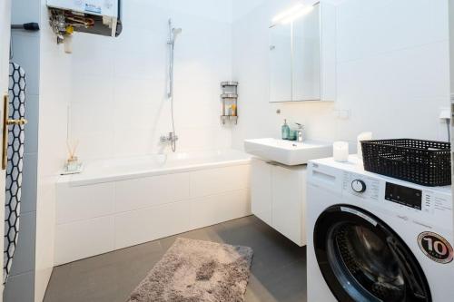 een witte badkamer met een wasmachine en een wastafel bij OrestaLiving - Spacious 2BR on the Danube Canal in Wenen