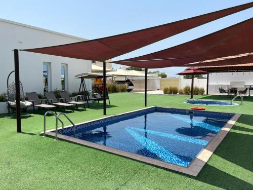 una piscina en un patio con sombrilla en Labella Chalet, en Barka