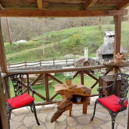 a porch with two chairs and a table and a grill at Σαν Παραμυθάκι in Filýra