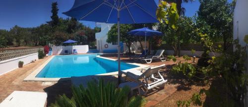 - une piscine avec 2 chaises et un parasol dans l'établissement Lugar das Andorinhas, à Albufeira