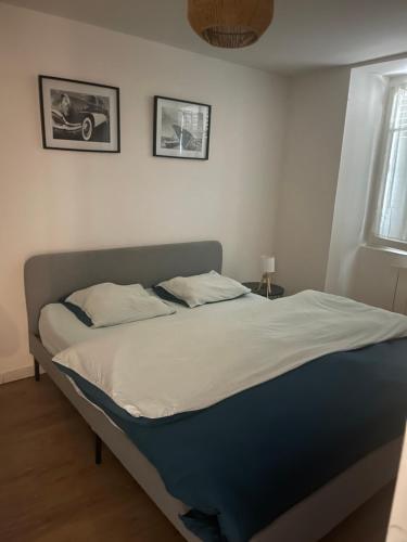 a bed in a bedroom with two pictures on the wall at Superbe Appartement in La Côte-Saint-André