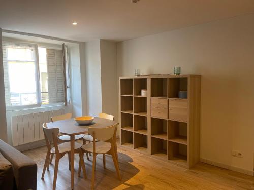 a living room with a table and chairs and a book shelf at Superbe Appartement in La Côte-Saint-André