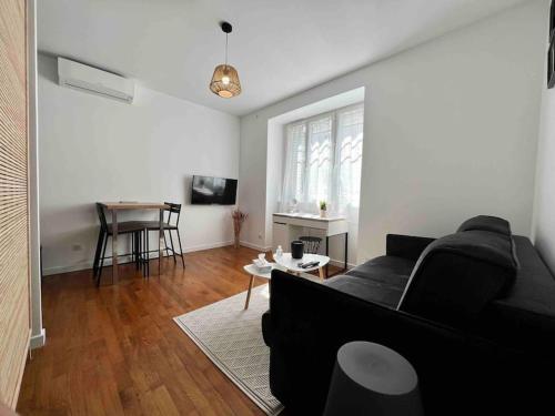 un salon avec un canapé noir et une table dans l'établissement Appartement Climatisé / Centre-ville / 4 personnes, à Besançon
