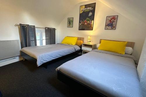 two beds with yellow pillows in a room at Agréable maison de ville 