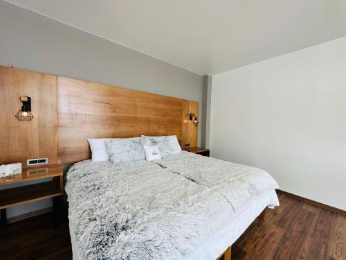 a bedroom with a large bed with a wooden headboard at Hotel La Mansión in San José Iturbide