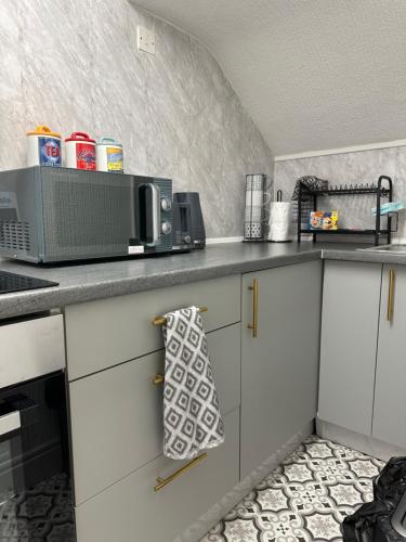 a kitchen with white cabinets and a microwave at Quirky Attic Blackpool in Blackpool