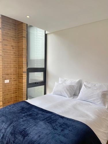 a bedroom with a large white bed with a window at Mitika Cultura movilidad y tranquilidad in Bogotá