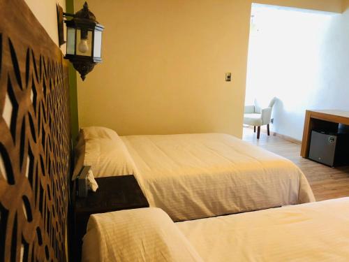a hotel room with two beds and a tv at Hotel La Mansión in San José Iturbide