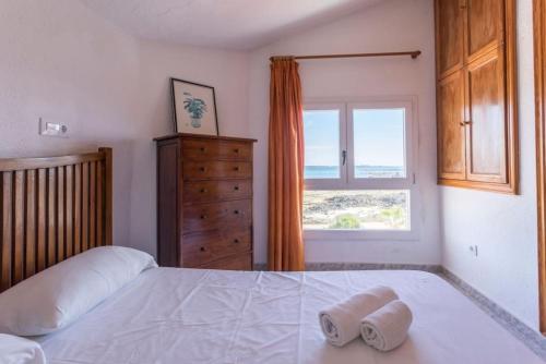 a bedroom with a bed and a dresser and a window at Corralejo Beachfront Villa Remos with Lobos Island View, Private Pool, Wifi & BBQ by Amazzzing Travel in Corralejo